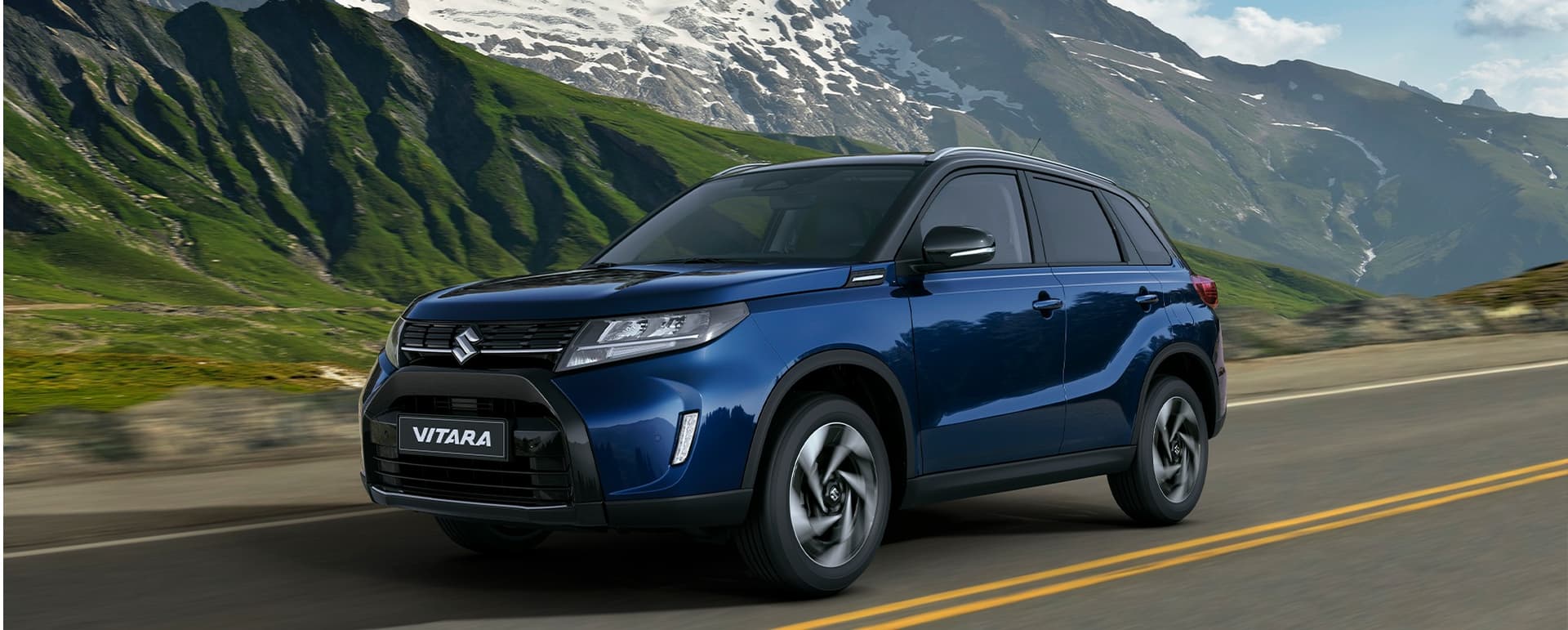 Suzuki Vitara hibrid indigókék gyöngyház és kozmikusfekete gyöngymetál fényezésben, hegyvidéki táj előtt