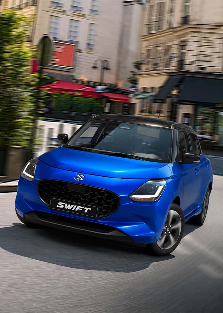 Zafírkék Suzuki Swift parkol egy forgalmas városi utcában